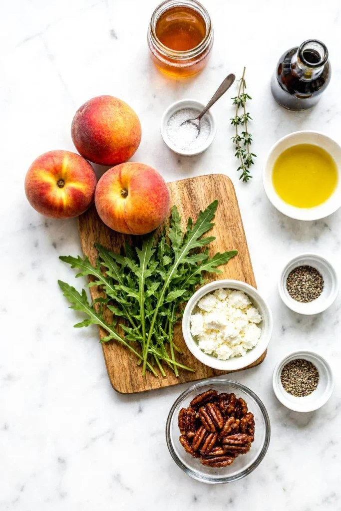 Fresh Peach Arugula Salad with Honey Balsamic Dressing 1 All ingredients for peach arugula salad arranged on white marble including peaches, arugula, goat cheese, pecans, and balsamic