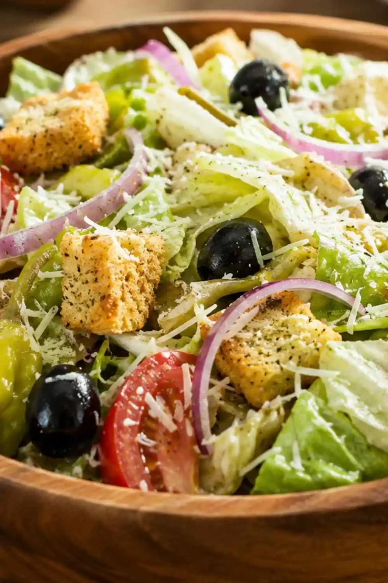 A large wooden bowl filled with authentic copycat Olive Garden salad topped with tomatoes, pepperoncini, black olives, croutons, and Parmesan cheese.
