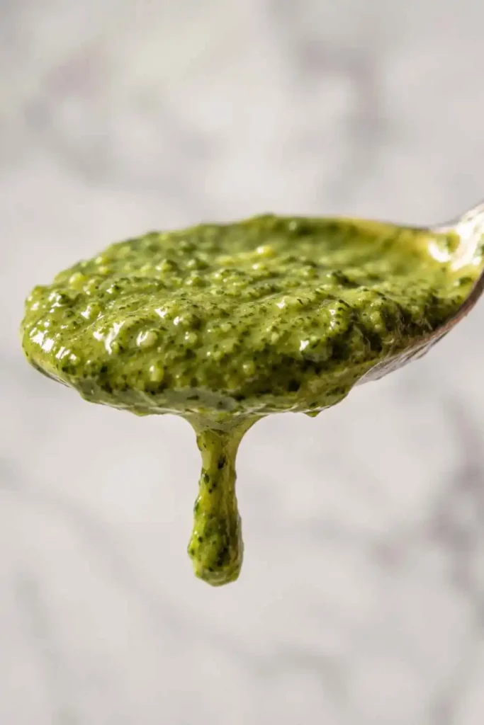 Creamy Pesto Sauce Recipe (Easy Restaurant-Style at Home) 4 Close-up of thick glossy creamy pesto sauce coating the back of a silver spoon showing velvety texture