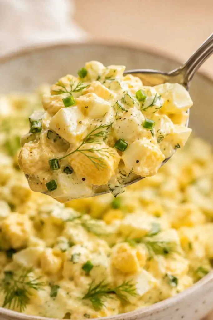 Classic Egg Salad Recipe – Creamy, Dijon & Dill 4 Close-up of classic egg salad recipe showing chunky hard-boiled egg pieces in creamy Dijon dressing with fresh dill on a spoon